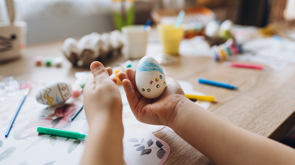 Child's hands holding Easter egg decorated by rhinestones